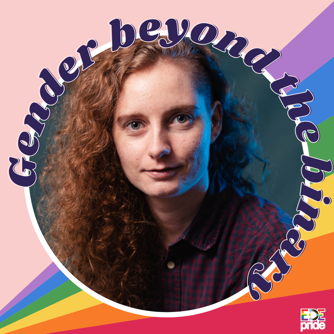 Afbeeldingsbeschrijving voor toegankelijkheid: Close-up van een wit persoon met lichtbruin, halflang krullend haar aan de ene kant en opgeschoren haar aan de andere kant. Diegene heeft lichte ogen, een kleine glimlach en een roodblauw geblokte blouse. De achtergrond is grijsblauw. In paarse letters staat rondom de tekst ‘Gender beyond the binary’.